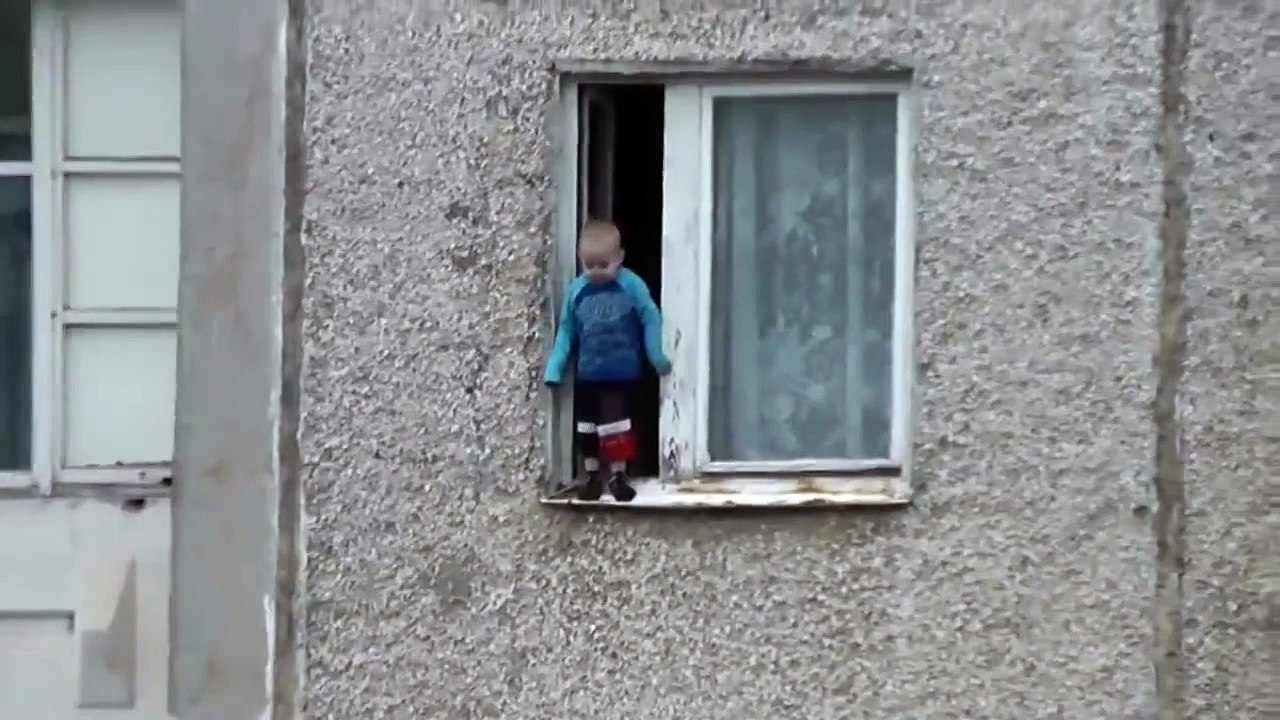 Un jeune enfant joue sur le bord d’une fenêtre au 8ème étage d’un immeuble