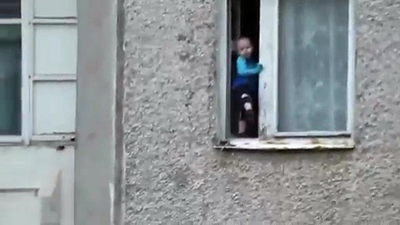 Un enfant s’amuse sur le bord d’une fenêtre au 8ème étage