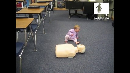 Baby girl practices CPR on a dummy