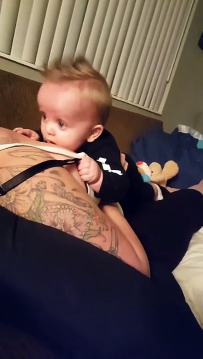 Un bebéjoue avec les seins de sa maman