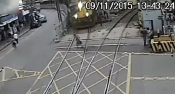 Un vieil homme traverse une voie ferrée juste devant un train