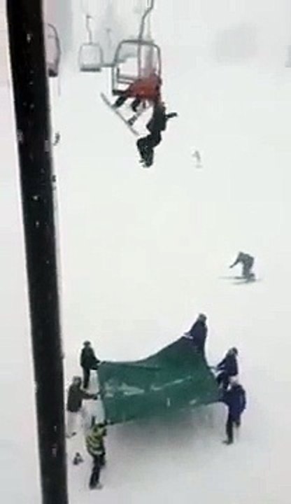 Snowboarder falls off of a chairlift