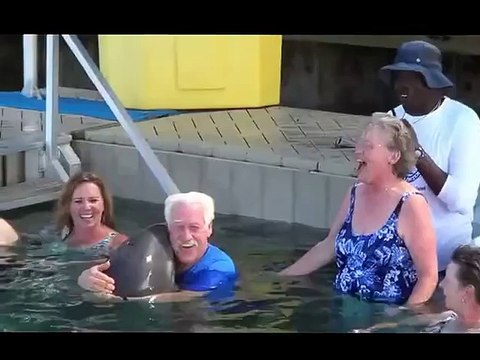 Un homme et un dauphin font un concours d'arrosage dans l'eau... Adorable