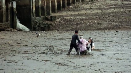 Un Thaïlandais aide deux touristes bloqués dans la boue