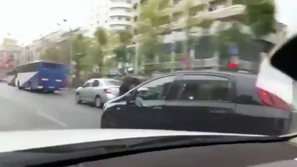 Une femme conduit avec un homme sur le capot
