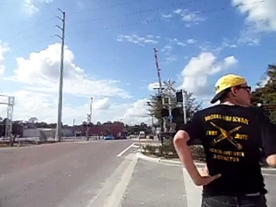 car fails to stop at a stop sign while boy waits for sunrail train