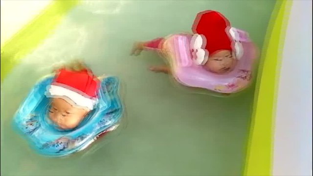 Twin babies swim adorably while wearing Santa outfits