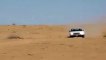 A small pickup truck climbs a giant sand dune - Toyota Hilux