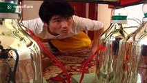 Martial artist stands on glasses without them breaking, while holding a bike in his mouth