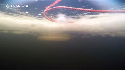Group of divers retrieve snowmobile from the bottom of a frozen river