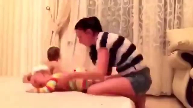 Молодая мама переодевает близнецов