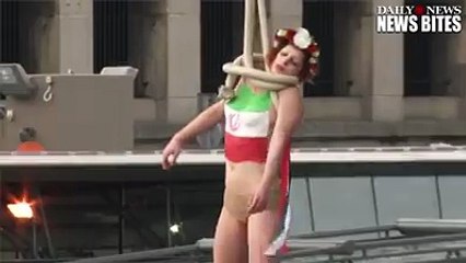 A topless woman with the Iranian flag painted on her chest staged a mock execution