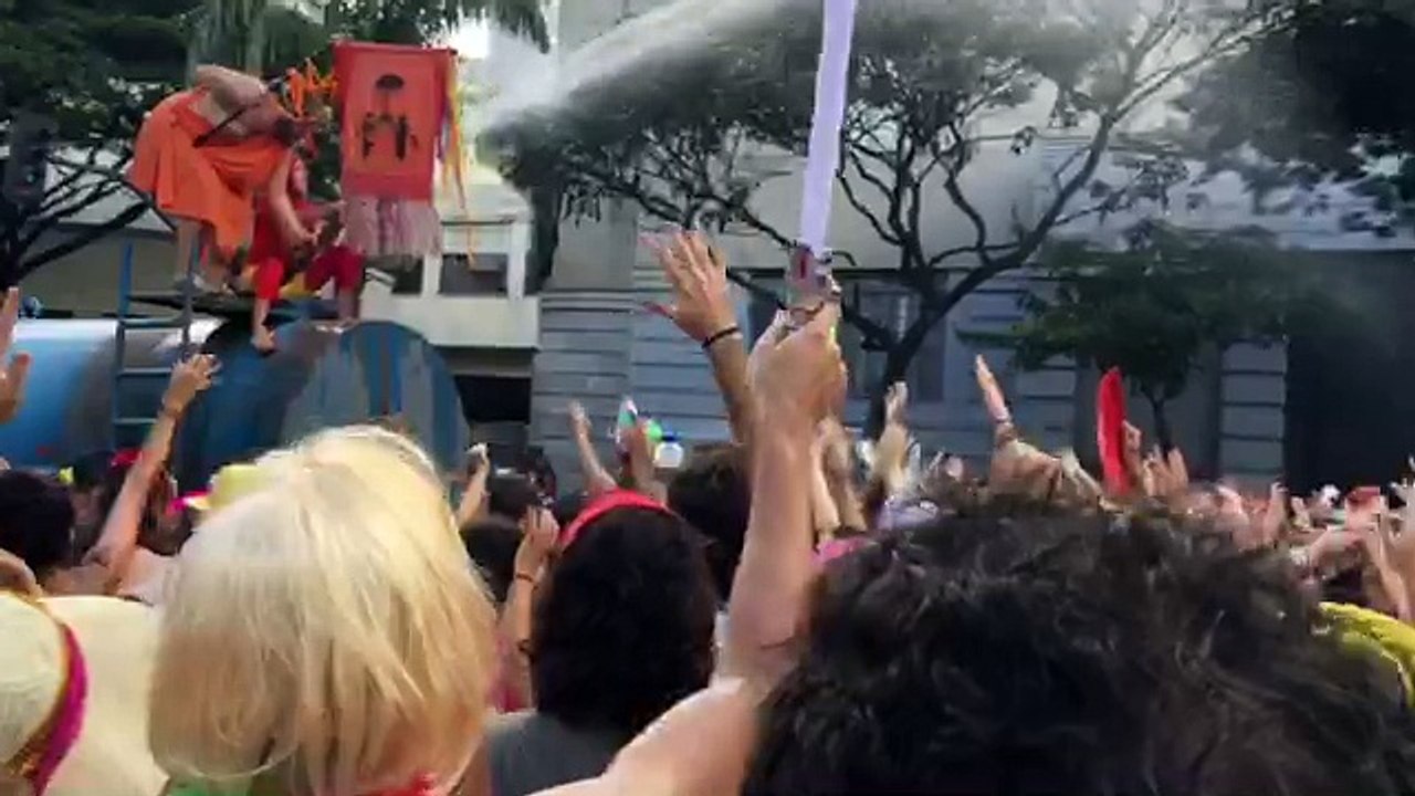 Foliões gritam enquanto se refrescam próximo ao caminhão pipa
