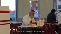 Un homme dévore ses burgers dans un fast-food