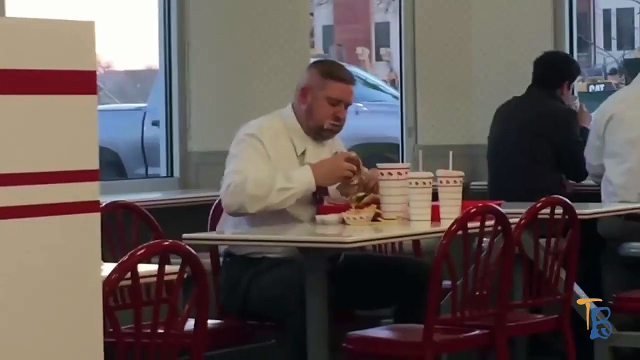 Un homme mange comme un porc dans un fast food