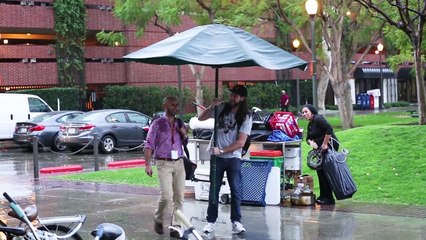 Caméra cachée: Il protège les gens de la pluie avec un parasol géant