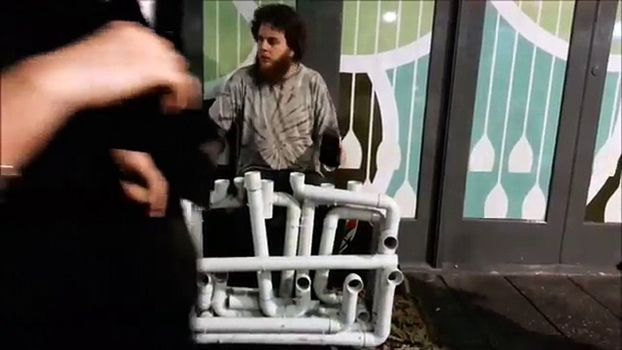 Уличный музыкант играет на водопроводных трубах