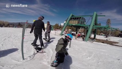 Three-year-old toddler learns to snowboard