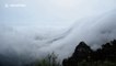 Absolutely stunning waterfall-like cloud formations in mountain range