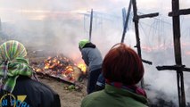 Démantèlement de la jungle de Calais, les migrants éteignent un feu de cabane