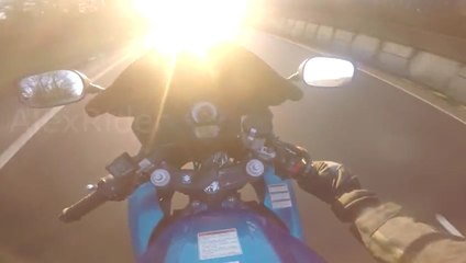 A motorcyclist blinded by the sun crashes against a car