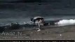 A guy waving a his family on the beach, see what happens next