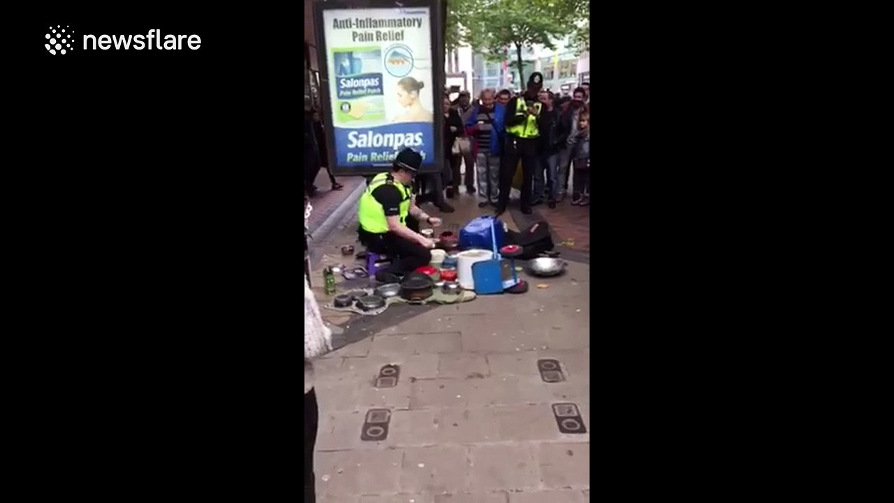 British policeman playing drums on pots and pans on the street