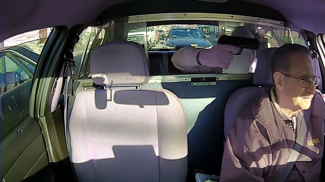 Un homme braque un chauffeur de taxi devant une voiture de police