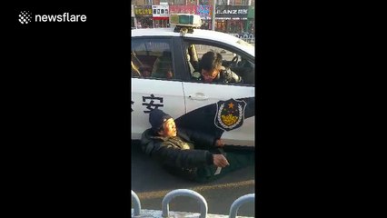 Man refuses to move from under police car