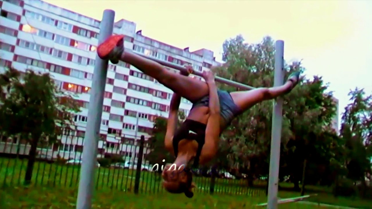Спортивная девушка в шортах разминается на турнике, Sports girl in shorts warming up on the bar