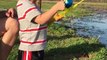 Un gamin attrape un gros poisson avec sa canne à pêche jouet.