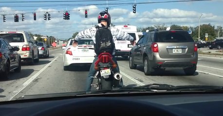 Un motard danse sur sa moto au feu rouge