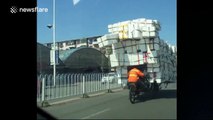Man rides heavily overloaded tricycle backwards on road