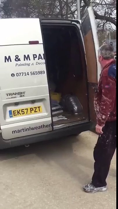 Un peintre recouvert de peinture dans une camionnette