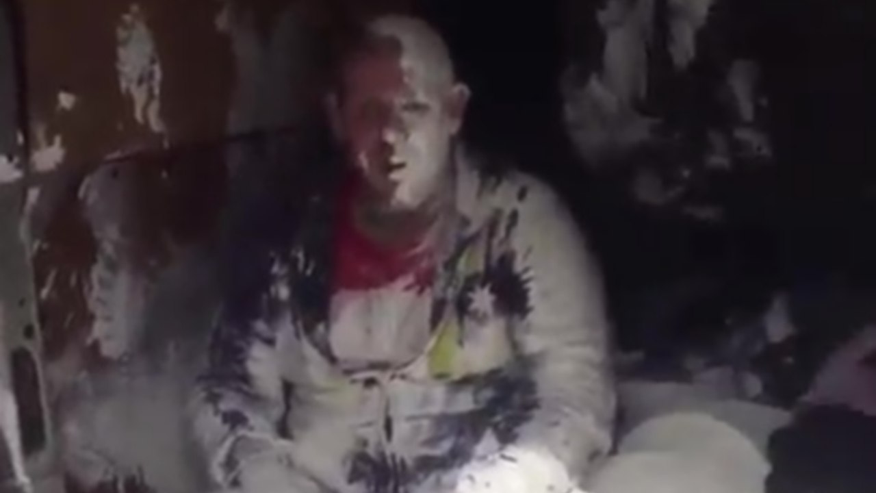 Un peintre à l'arrière d'un camion se prend un seau de peinture