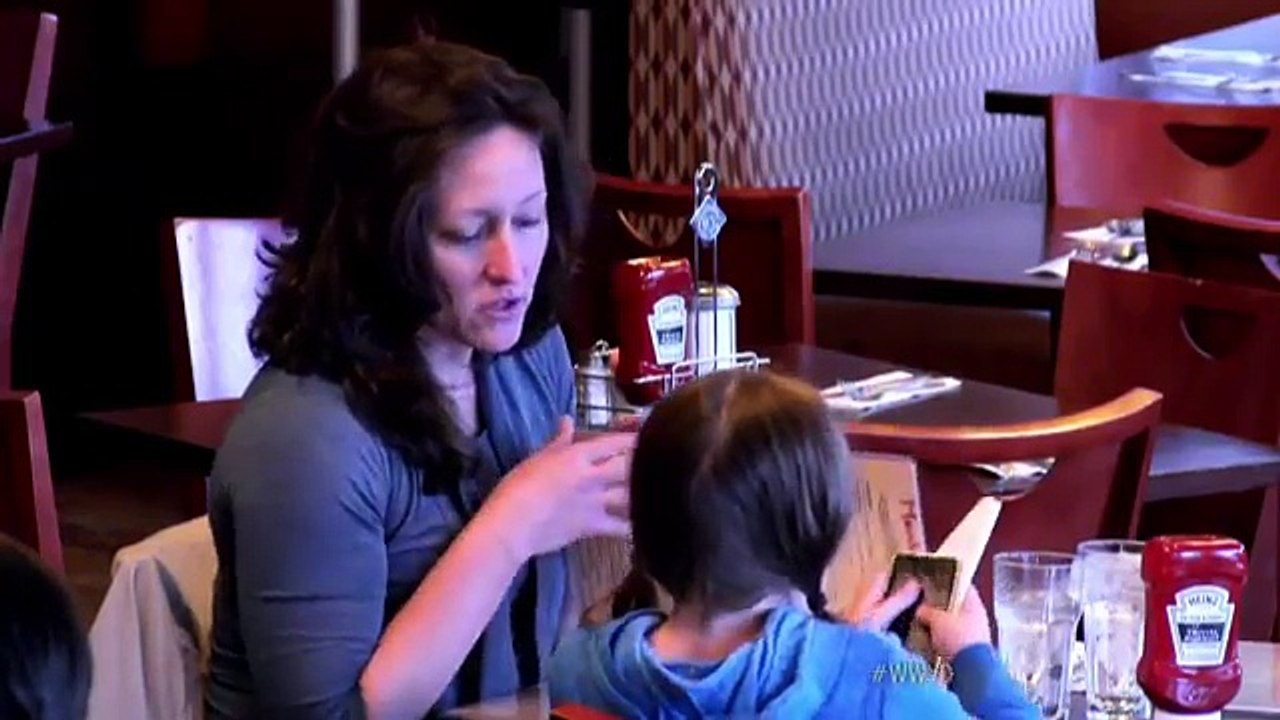 Pendant que le fils adoptif crève de faim, la "mère" et la petite se régalent. Voyant la scène, les clients réagissent..