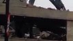 Une pelleteuse traverse le toit d'un parking qu'elle est en train de démolir.