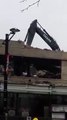Une pelleteuse traverse le toit d'un parking qu'elle est en train de démolir.