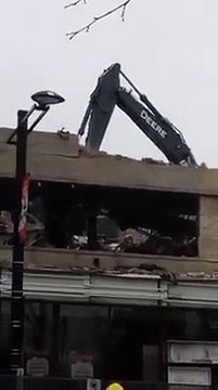 Une pelleteuse traverse le toit d'un parking qu'elle est en train de démolir.