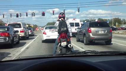 Un motard danse sur sa moto au feu rouge