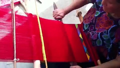 Mujer artesana de Zinacantán tejiendo a mano en telar de cintura.