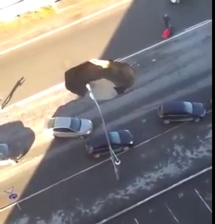 La route s'effondre et un trou béant menace d'avaler les voitures qui roulent dessus