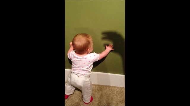 Ce bébé jour avec l'ombre chinoise de la main de sa maman au mur...