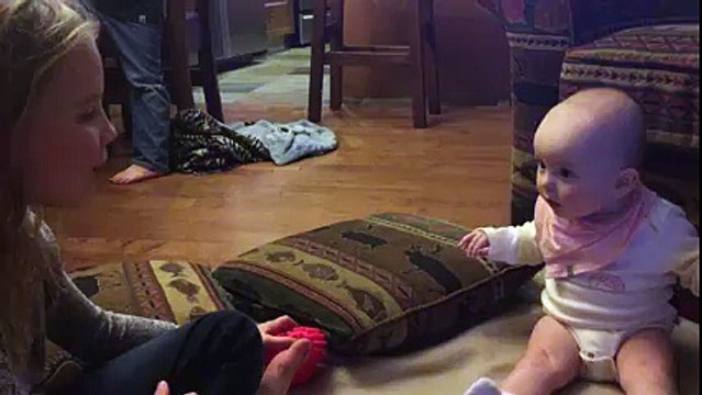 Un bébé fasciné par sa soeur qui fait des bulles de chewing gum