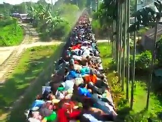 A train in india extremely loaded with passengers on the roof