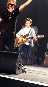 Jean-Louis Aubert invite un enfant à jouer de la guitare en plein concert des Insus