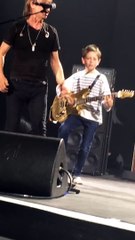 Jean-Louis Aubert invite un enfant à jouer de la guitare en