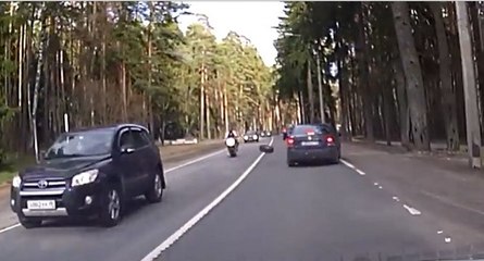 Un motard malchanceux chute à cause d'une roue de voiture
