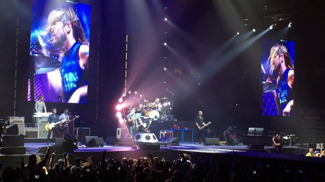 Un fan monte sur scène chanter Tom Sawyer de Rush lors d'un concert des Foo Fighters