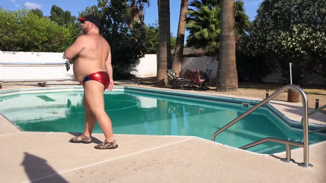 Un homme danse au bord d'une piscine en maillot de bain